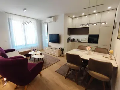 a living room with a table and chairs and a kitchen at Kalemegdan Park Residence - new luxury apartment in Belgrade