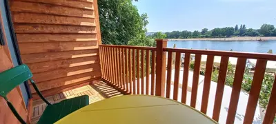 a wooden balcony with a table and chairs and a lake at Island Ada in Čukarica