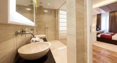 a bathroom with a large sink and a bedroom at Eden Garden Suites in Belgrade