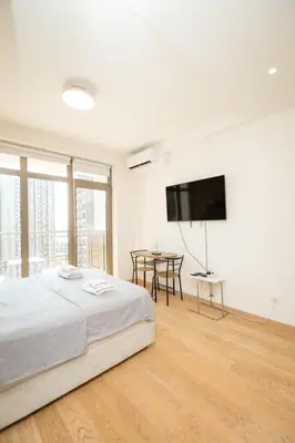 a white bedroom with a bed and a flat screen tv at Belgrade Waterfront Nimax in Sajmište