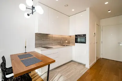 a kitchen with white cabinets and a wooden table at West 21 Tower in Fontana