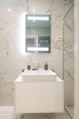 a white bathroom with a sink and a mirror at West Tower Luxury in Fontana