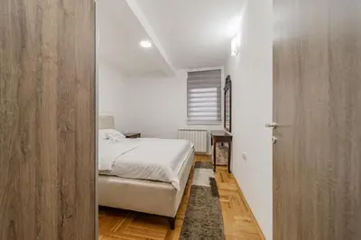 a bedroom with a white bed and a wooden door at Port 1 in Belgrade