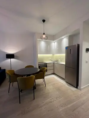 a kitchen with a table and chairs and a refrigerator at Apartman Julija in Sajmište