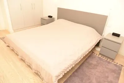 a bedroom with a white bed with a purple rug at Apartman Julija in Sajmište