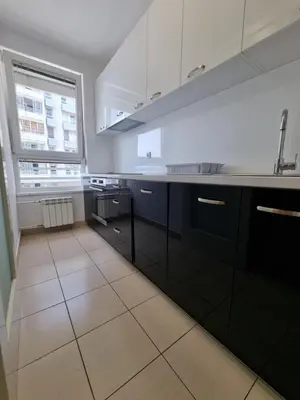 a kitchen with black and white cabinets and a window at Euforia apartment in Novi Beograd