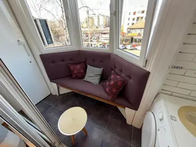 a purple couch in a small room with two windows at Hedonic Studio in Belgrade