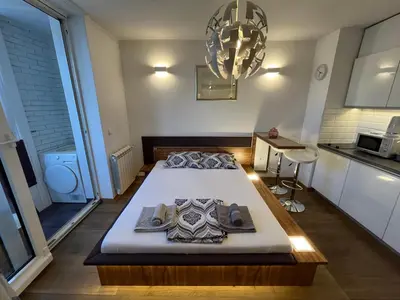 a large bed in a room with a kitchen at Hedonic Studio in Belgrade