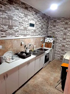 a kitchen with white cabinets and a stone wall at Sunny Side Fruska Gora- apartman A in Velika Remeta