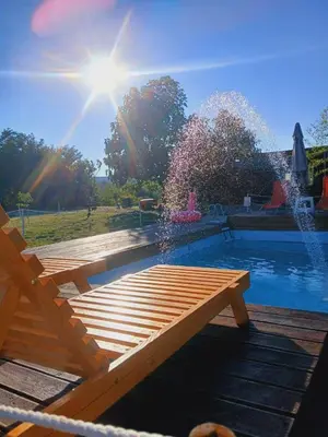 a wooden bench next to a pool with a fountain at Sunny Side Fruska Gora- apartman A in Velika Remeta