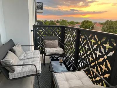 a balcony with two chairs and a dog on a table at Luxe Living Modern Apartment Stara Pazova in Stara Pazova