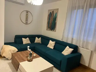 a living room with a blue couch and a table at Luxe Living Modern Apartment Stara Pazova in Stara Pazova