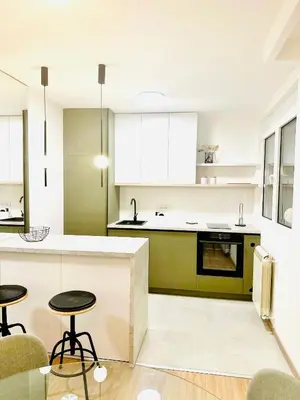 a kitchen with white and green cabinets and stools at Angelo S in Belgrade