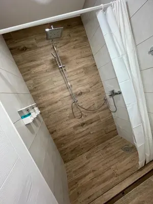 a shower in a bathroom with a wooden floor at Airport Apartments Alexandra in Surčin