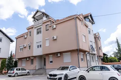 a building with two cars parked in front of it at RoofTop in Arandjelovac