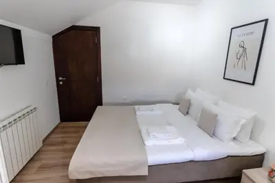 a bedroom with a bed with white sheets and a television at RoofTop in Arandjelovac