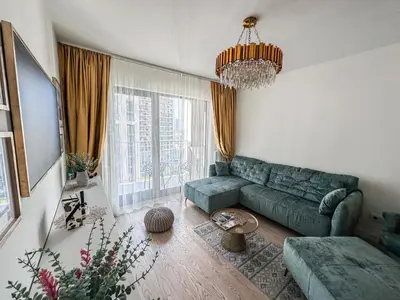 a living room with a green couch and a chandelier at Beldorado Apartments - Belgrade Waterfront Luxury Emerald Apartment 60m2 in Belgrade