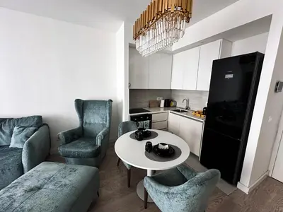 a living room with a table and chairs and a kitchen at Beldorado Apartments - Belgrade Waterfront Luxury Emerald Apartment 60m2 in Belgrade