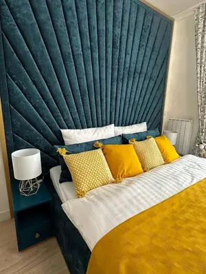 a bed with a blue headboard and yellow pillows at Beldorado Apartments - Belgrade Waterfront Royal Luxury Studio in Belgrade