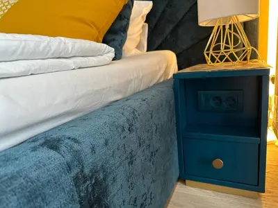 a blue nightstand next to a bed with a lamp on it at Beldorado Apartments - Belgrade Waterfront Royal Luxury Studio in Belgrade