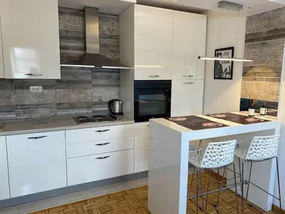 a kitchen with white cabinets and a island with bar stools at Fellini Apartment in Belgrade