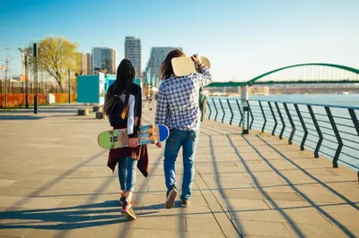 a man and a woman walking down a sidewalk with a skateboard at Fellini Apartment in Belgrade