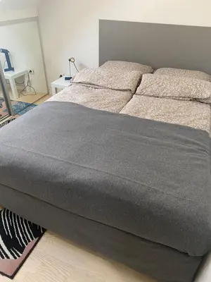 a bed in a bedroom with a gray blanket on it at Fellini Apartment in Belgrade