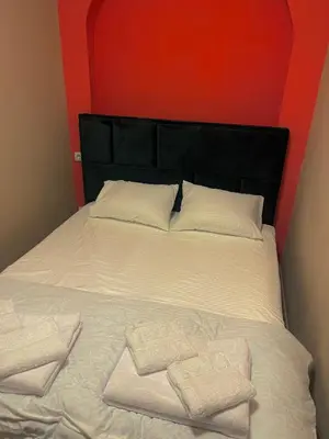 a bed with two towels on it with a red headboard at Mystique Spa Apartment in Belgrade