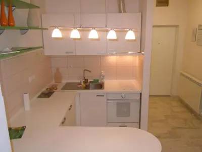 a kitchen with white cabinets and a sink and lights at Porto Studio in Belgrade