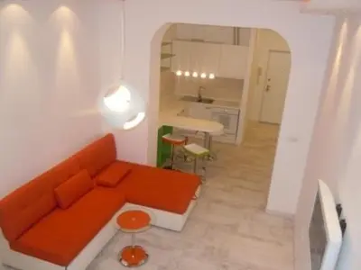 a living room with an orange couch and a kitchen at Porto Studio in Belgrade