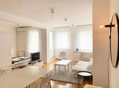 a white living room with a table and a tv at Miu Arena Apartment in Belgrade