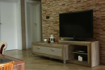 a living room with a television on a brick wall at Apartman Avala Beograd in Beli Potok