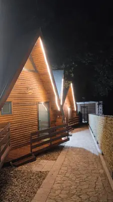a wooden cabin with lights on the side of it at Planinske Kuće Grocka in Grocka