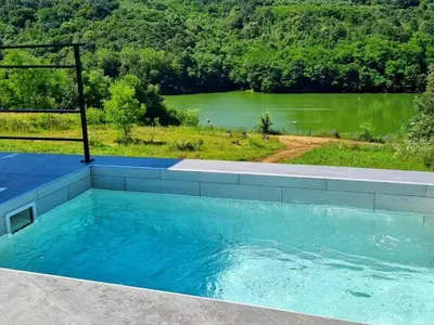 a large swimming pool with a view of a lake at Glamping A frame lake Heated pool in Barajevo