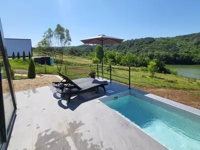 a pool with a picnic table and an umbrella at Glamping A frame lake Heated pool in Barajevo