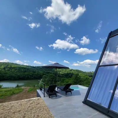 a patio with two chairs and an umbrella at Glamping A frame lake Heated pool in Barajevo
