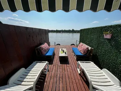a wooden deck with two chairs and a table and a table and chairs at Splav na reci Savi in Ostružnica
