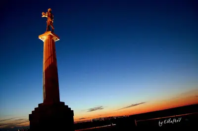 a statue on top of a monument with the sunset in the background at Belgrade Square 1 Apartment in Belgrade