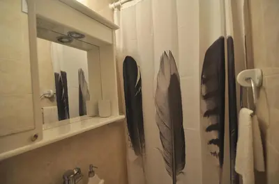 a bathroom with a mirror and black feathers on the wall at Charming studio near downtown in Belgrade