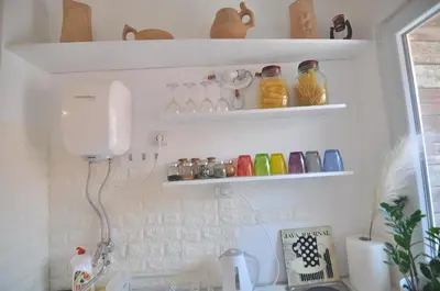 a kitchen with a sink and shelves with glass jars at Charming studio near downtown in Belgrade