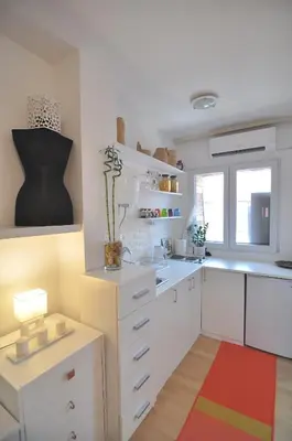 a kitchen with white cabinets and a colorful rug at Charming studio near downtown in Belgrade