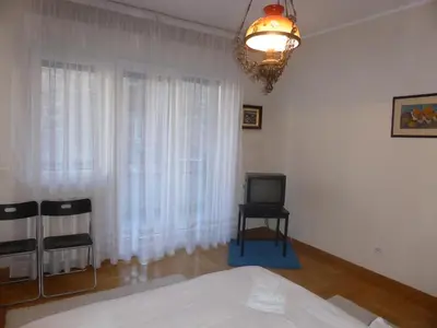 a bedroom with a bed and a television and a chandelier at Apartment Deligradska in Belgrade