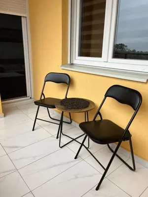 two chairs and a table in front of a wall at Apartman Maša in Ruma