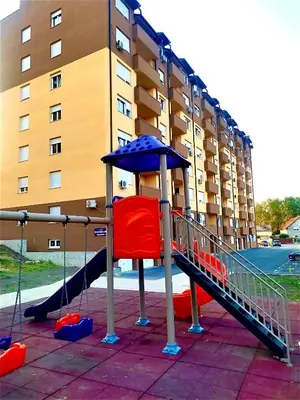 a playground in front of a building with a slide at Apartman Maša in Ruma