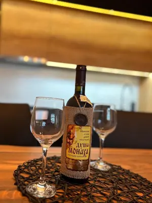 a bottle of wine sitting on a table with two glasses at Apartman Maša in Ruma
