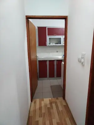 a small kitchen with red cabinets and a hallway at Jasna in Zemun