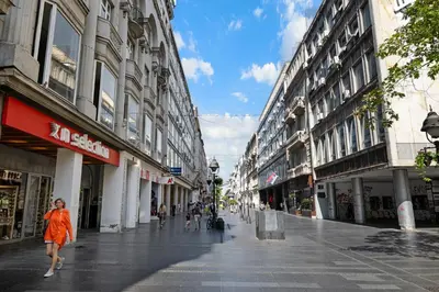 a woman in an orange dress walking down a city street at Prince Rooftop in Belgrade