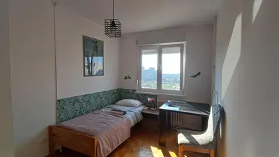 a bedroom with a bed and a desk and a window at Sobe AURORA Nehruova 82 in Belgrade