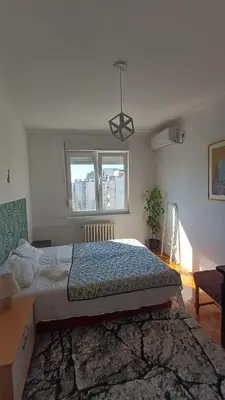 a bedroom with a bed and a desk and a window at Sobe AURORA Nehruova 82 in Belgrade