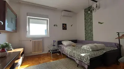 a bedroom with a bed and a table and a window at Sobe AURORA Nehruova 82 in Belgrade